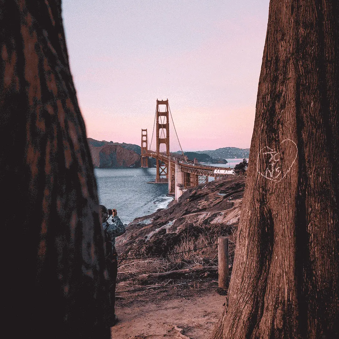 A view of the Golden Gate bridge through a gap in two rocks during sunset