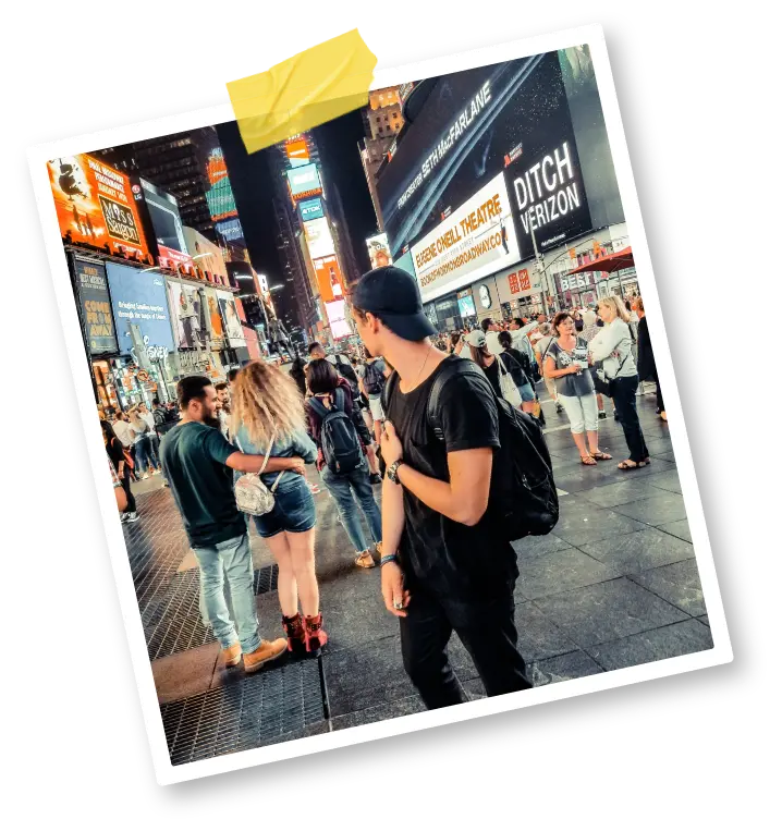 A young man in a baseball cap on Times Square at night