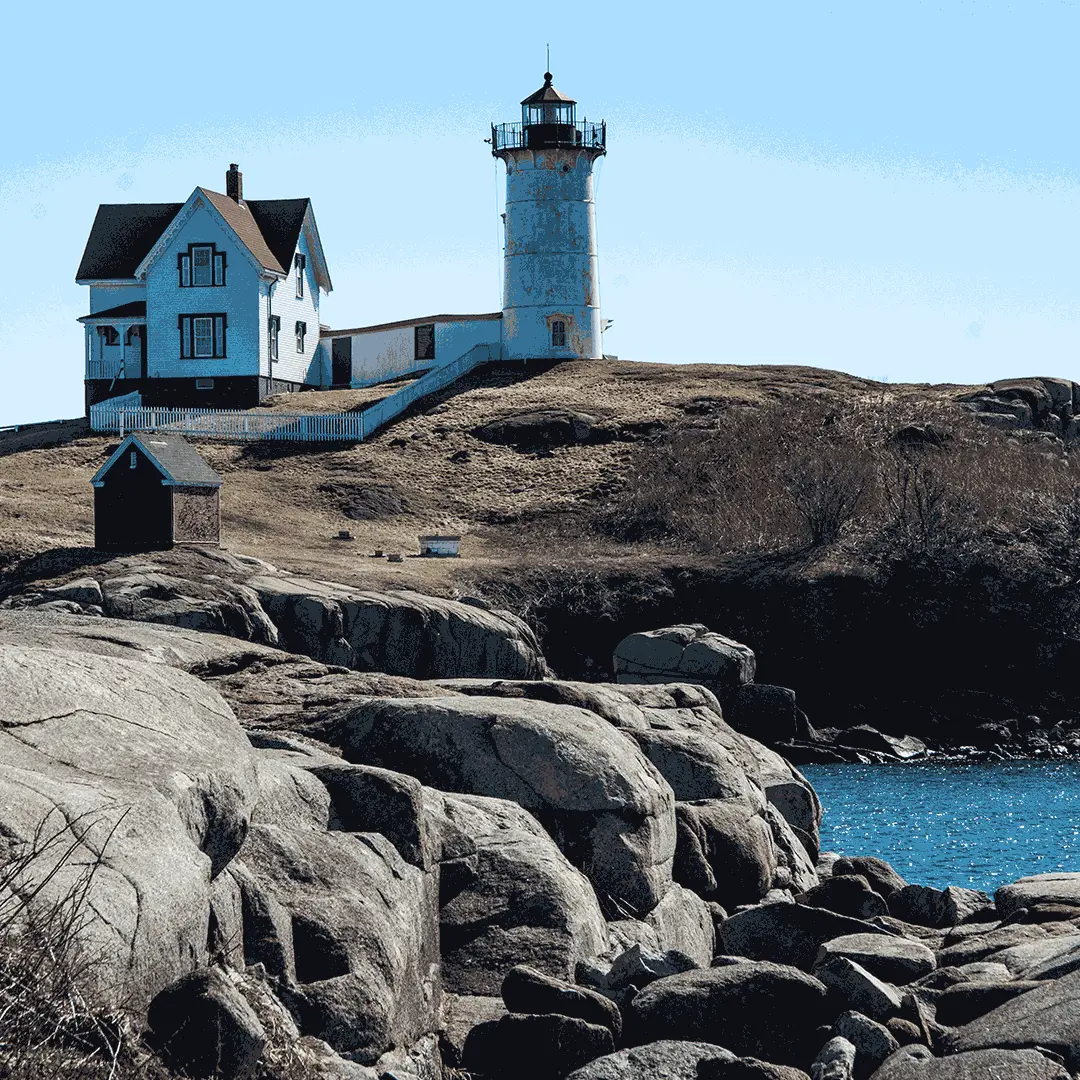 A white clad building and lighthouse on a Cape Cod cliff in the daytime