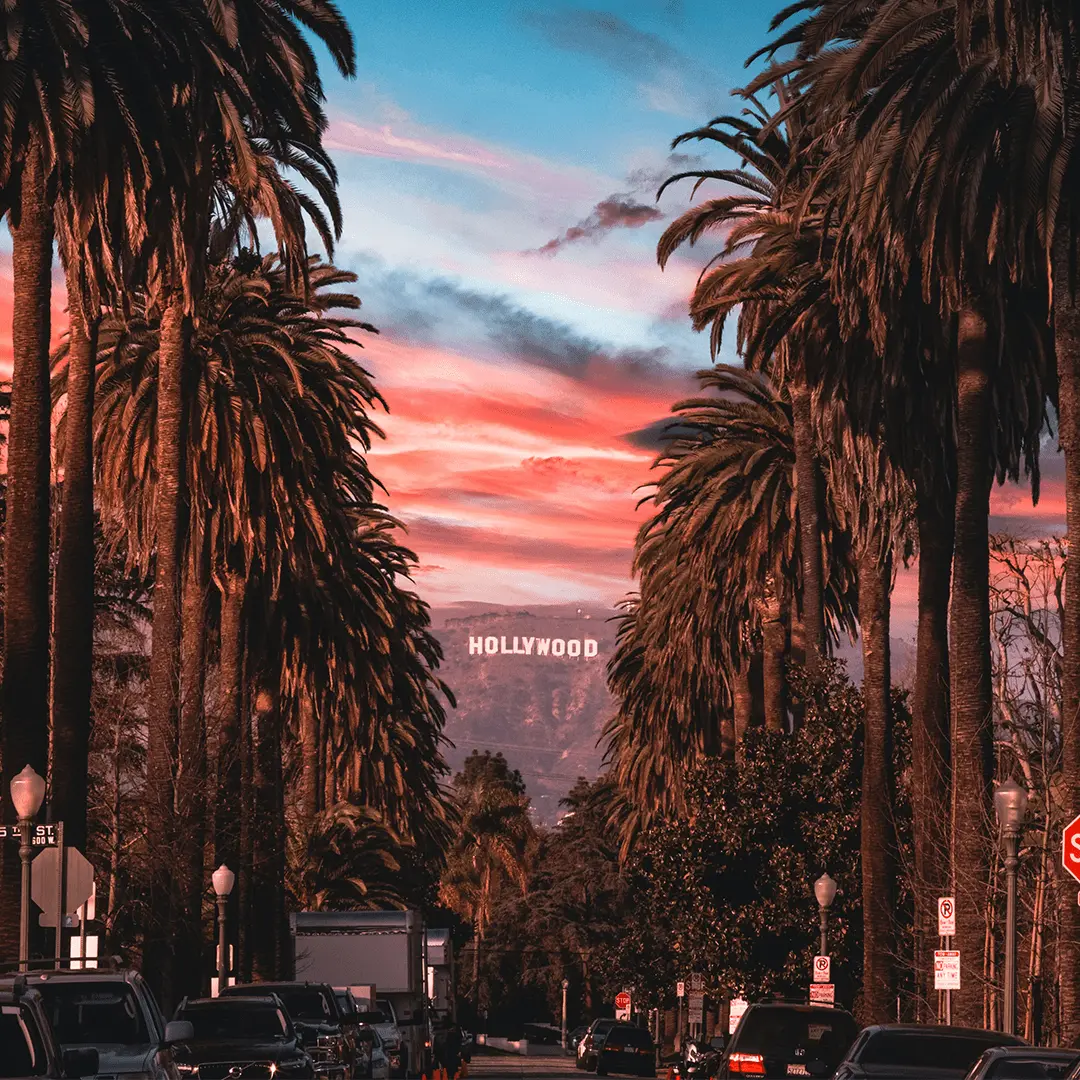 A view of the Hollywood sign from a street in Los Angeles at twilight under a multicoloured sky